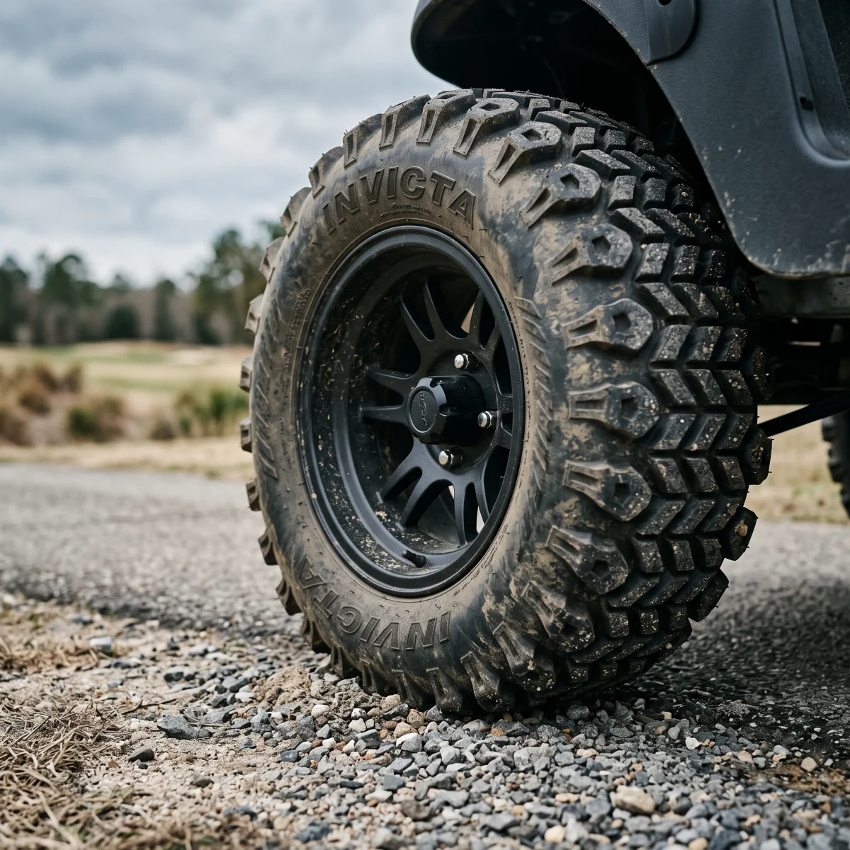 INVICTA SAHARA CLASSIC directional chevron lugs biting into loose gravel at the edge of a cart path